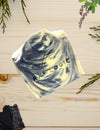 Hexagonal soap bar with 'Raw Logic' branding on a wooden surface with greenery.