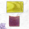 Two soap bars from RAWLOGIC on a marble surface with purple flowers.