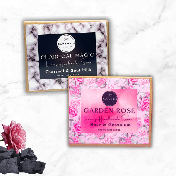 Two soap packages, one labeled 'Charcoal Magic' and the other 'Garden Rose', on a marble surface with decorative elements.
