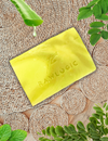Yellow soap bar with 'RAWLOGIC' on a woven mat with green leaves.